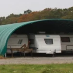 Un très grand abri agricole avec trois caravanes dessous